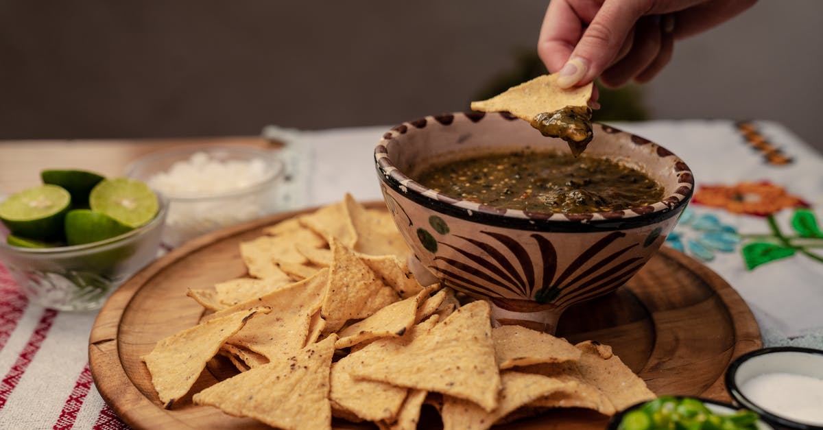 Getting crispy banana chips - A Person Dipping Chips on Salsa 