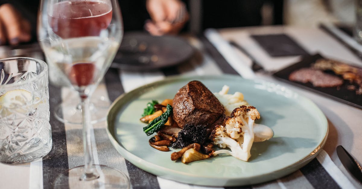 Getting dog meat to taste as close to steak as possible? - Tasty grilled steak served with cauliflower and mushrooms placed on table with wineglass filled with alcohol drink in restaurant on blurred background