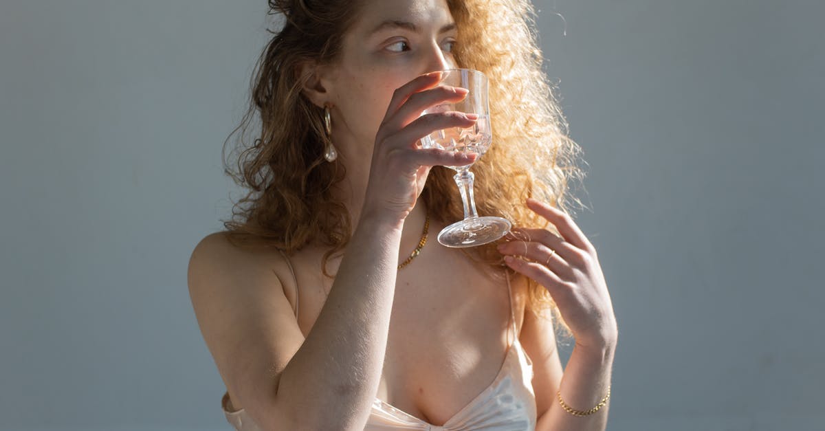 Glass drink dispenser for vinegar long term storage? - Young female with curly hair bare shoulders and chest looking away while drinking water on white background