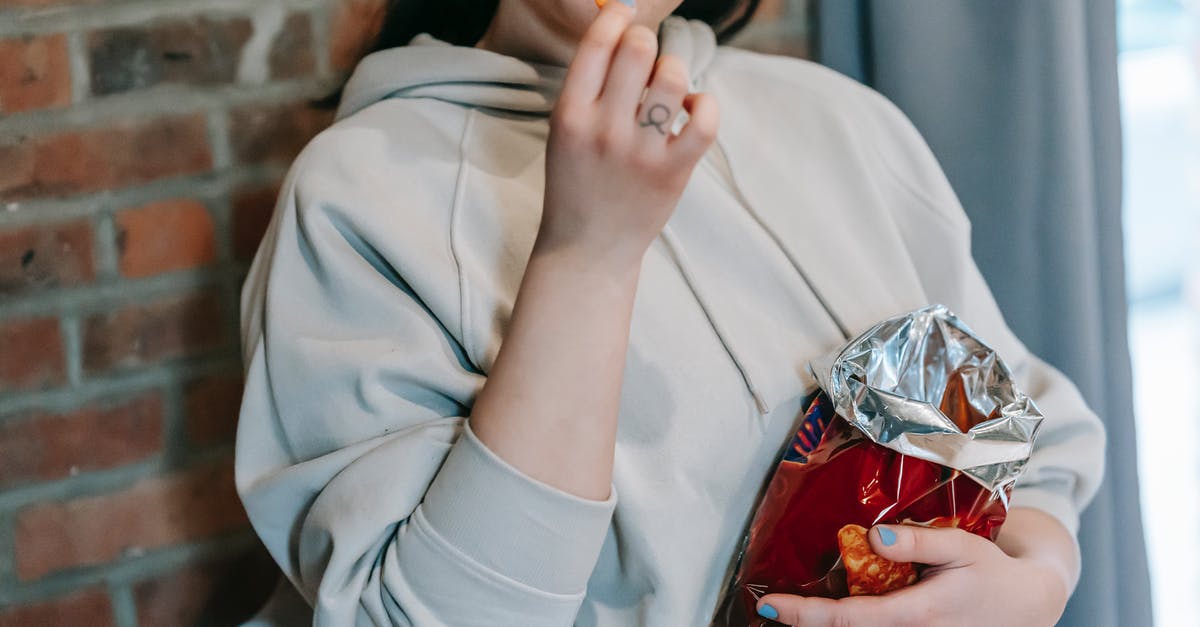 gluten free gnocchi tasting too much like potato - Crop plump female in casual hoodie enjoying crispy baked breads and licking lips against brick wall