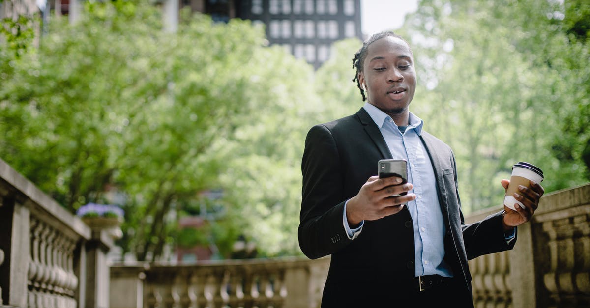 Good programmable coffee urn solution - Positive young black man with smartphone and takeaway coffee in city park