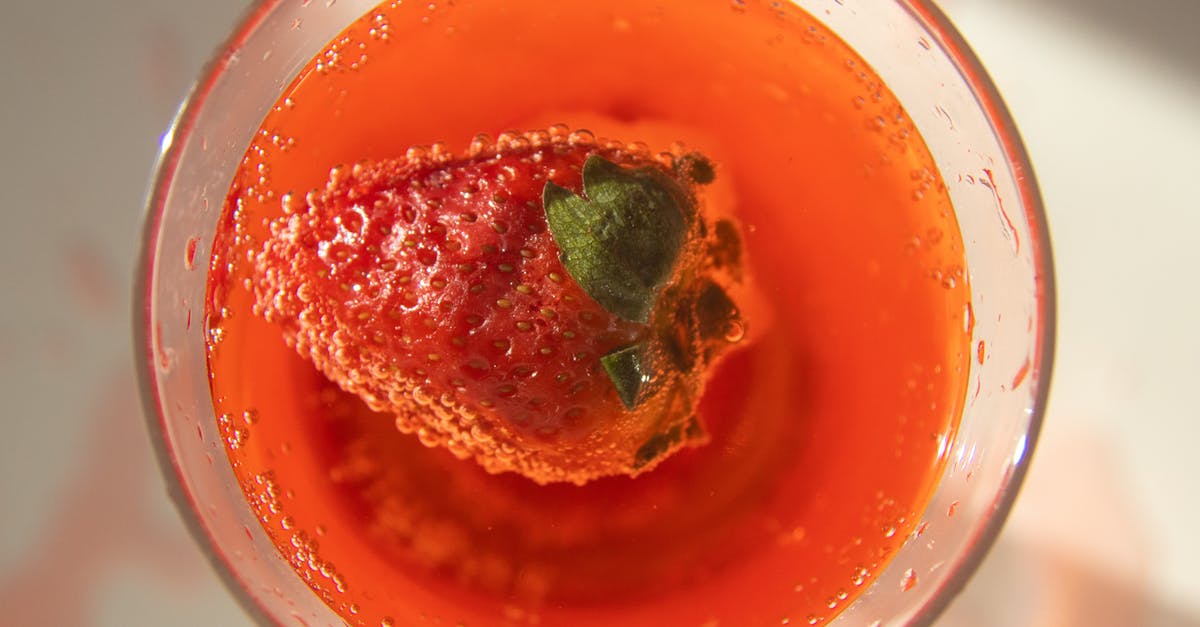 Grape Juice left out overnight, now has fizz - Top view of fresh red strawberry in glass of cold cocktail served on white table in sunlight