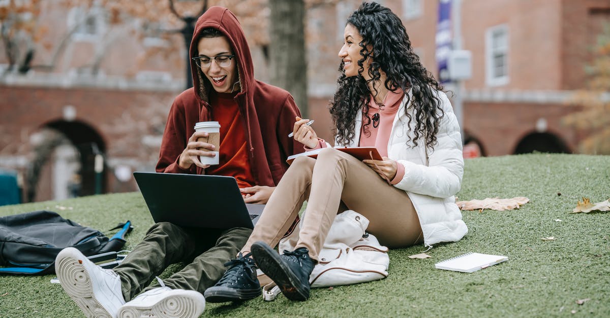 Grassy Tea and brands - Multiethnic friends studying with notepad and netbook on grassy field