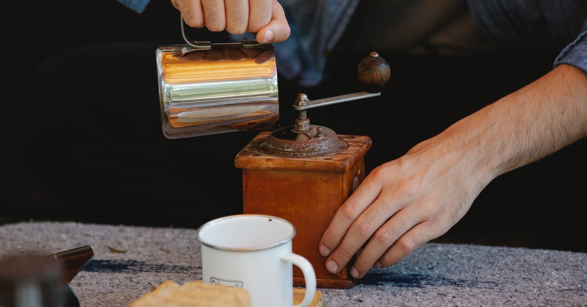 Grind coffee with a blade grinder for a moka pot? - Crop unrecognizable male pouring water into manual coffee grinder placed on table before coffee brewing