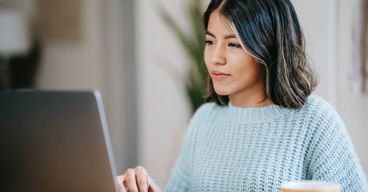 Grinding loose Green Tea for more concentration - Confident young Latin American woman in casual clothes working remotely on netbook at table near mug with coffee in light apartment with plant with green leaves near wall