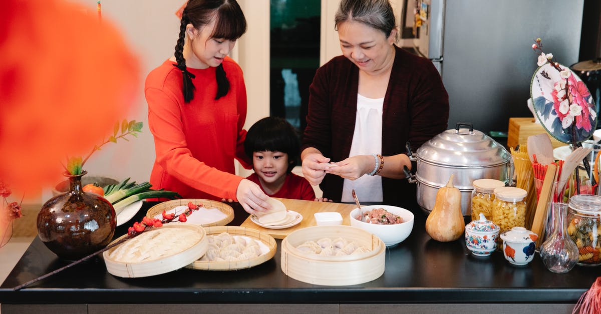 Ground beef smells slightly sweet? - Content ethnic grandma with female teenager and grandson cooking dim sum at table with steamer in house