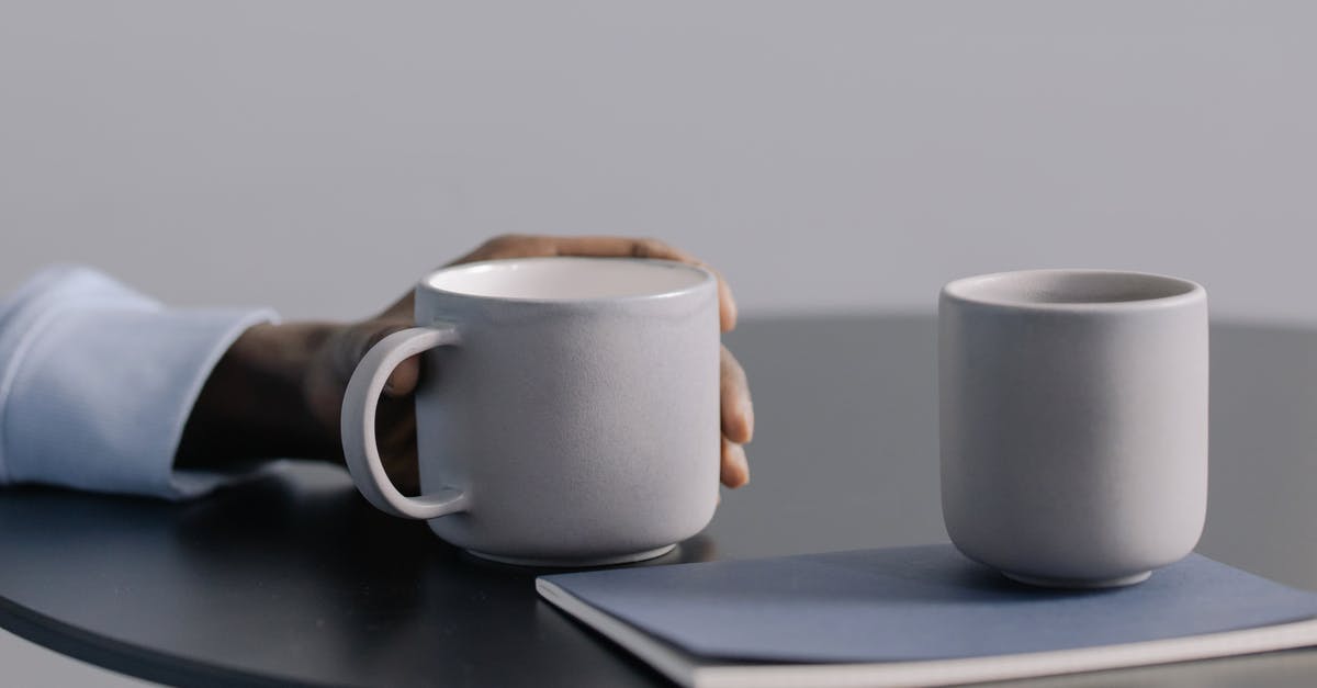 hand cranked ceramic conical burr coffee grinder? [closed] - Person Holding White Ceramic Mug on Black Table