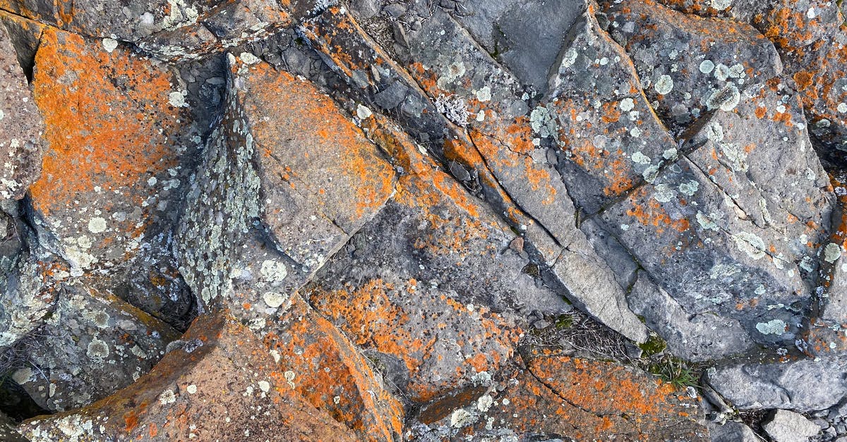 Hard anodized wok without scratch-resistant coating? - Top view of rough natural rock surface with cracks and orange rust as abstract  background