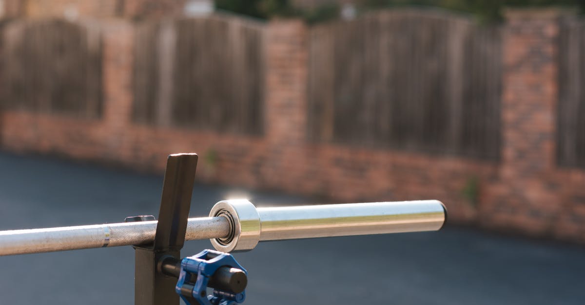 Hard boiled eggs outside the fridge - Part of steel barbell without weight discs for training on stand against fence in sunlight