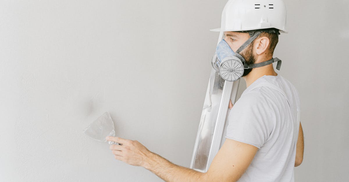 Hard to find spatula [duplicate] - Man in White T-shirt Wearing White Gas Mask Using Flat Metal Spatula on the Wall