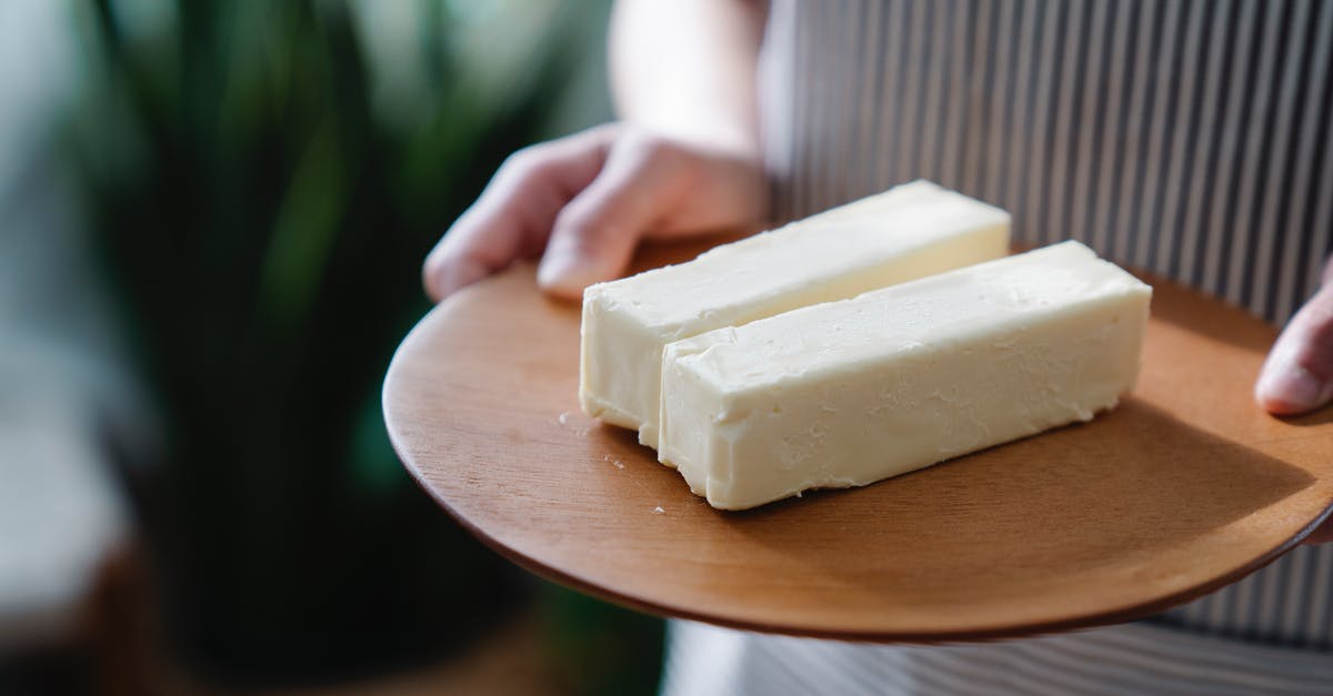 Has anyone ever made margarine out of butter? [closed] - Close-Up Shot of a Person Holding a Wooden Plate with Sliced Butters