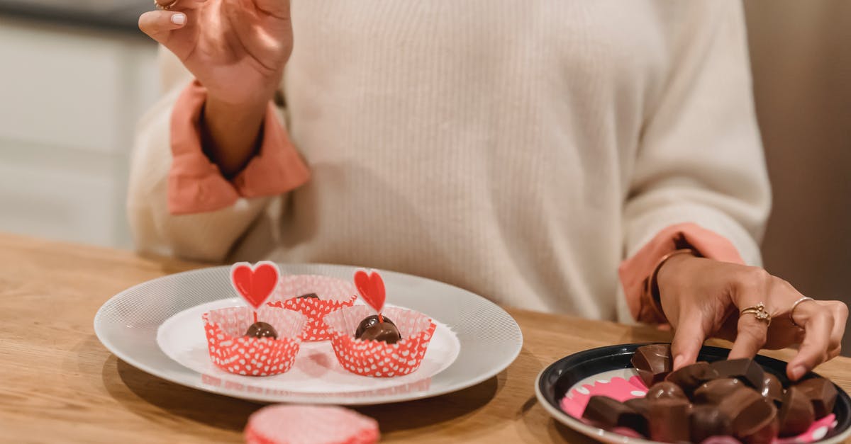 Heart shaped mold - Unrecognizable female serving sweet chocolate candies into molds on plate decorated with red hearts while standing near table in kitchen at home