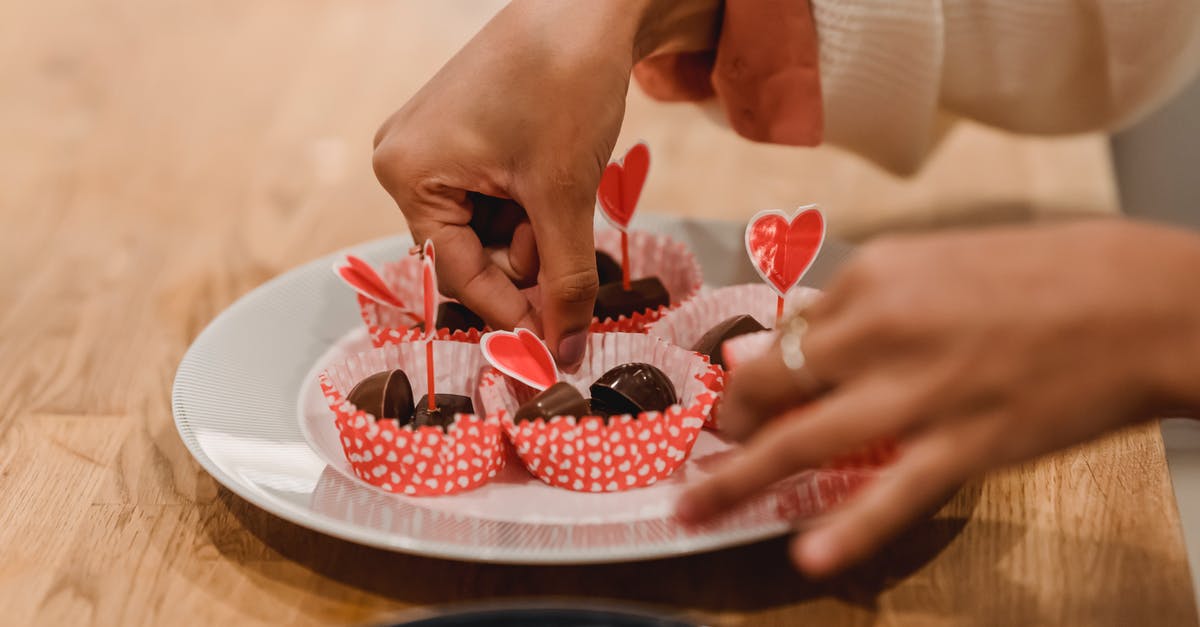 Heart shaped mold - Unrecognizable female cook arranging sweet candies into molds on plate decorated with red heart while standing at table in kitchen