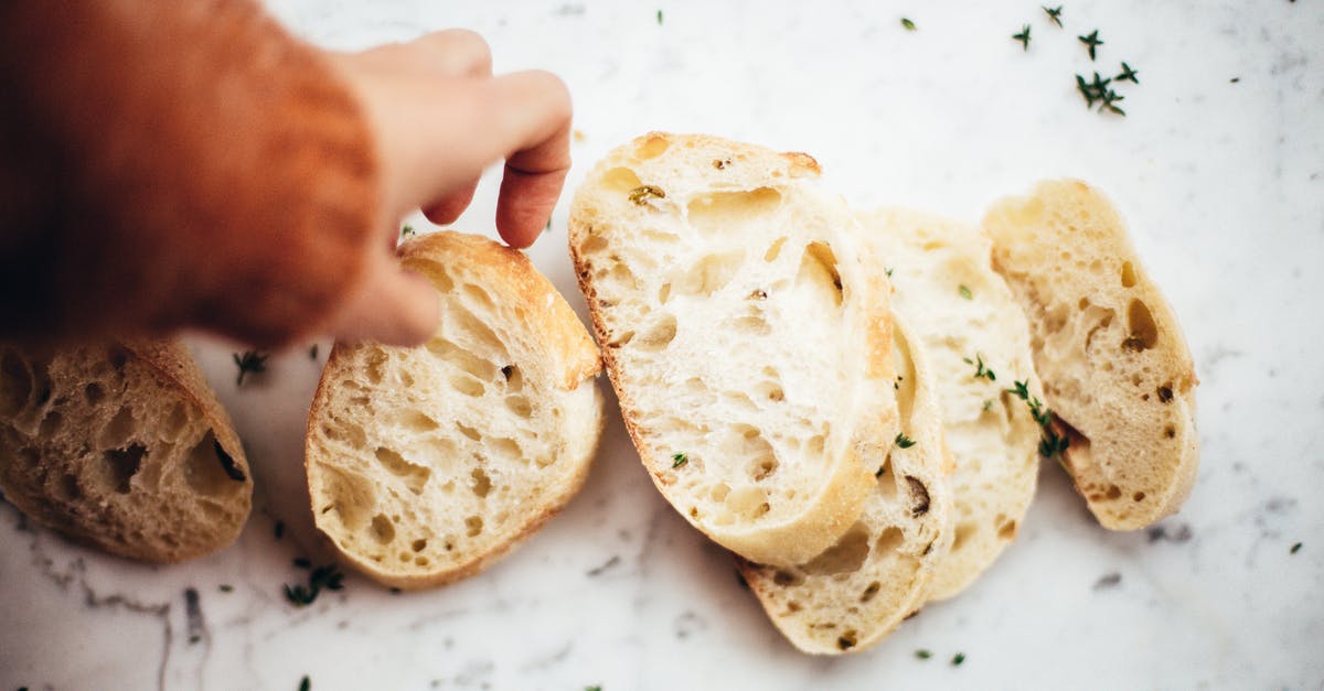 Heating part baked baguettes in lid-covered pyrex - Slices of bread on table