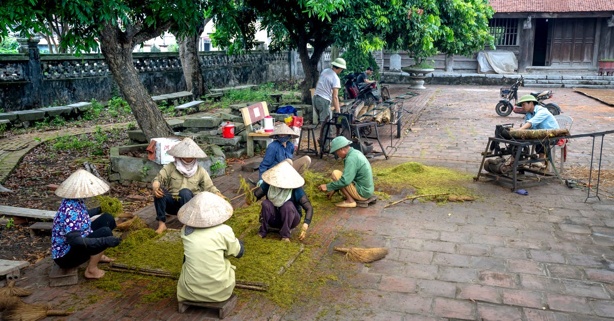 Help identifying a tea - Unrecognizable ethnic people in conical hats placing ground tea foliage on tray while sitting on walkway in town