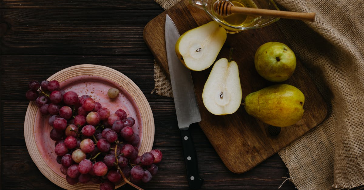 Help in identifying Scandinavian dessert recipe - Top view composition of cut pears with honey in bowl on cutting board and plate with grapes on wooden rustic table