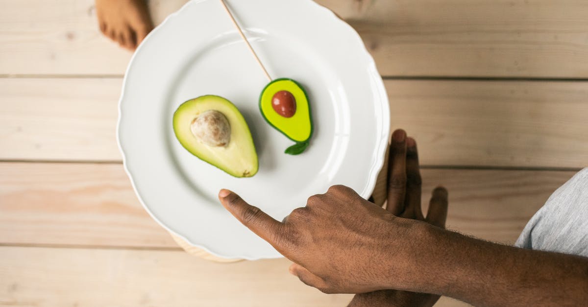 Help needed to identify the seeds - Top view of crop anonymous African American man pointing on organic healthy avocado helping child to choose between natural fruit and sweet lollipop