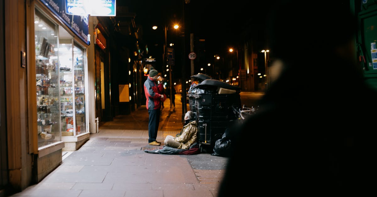 Help roaster oven quit in the night! [duplicate] - Anonymous man giving money to poor beggar on tiled sidewalk near shop showcases in town at dusk