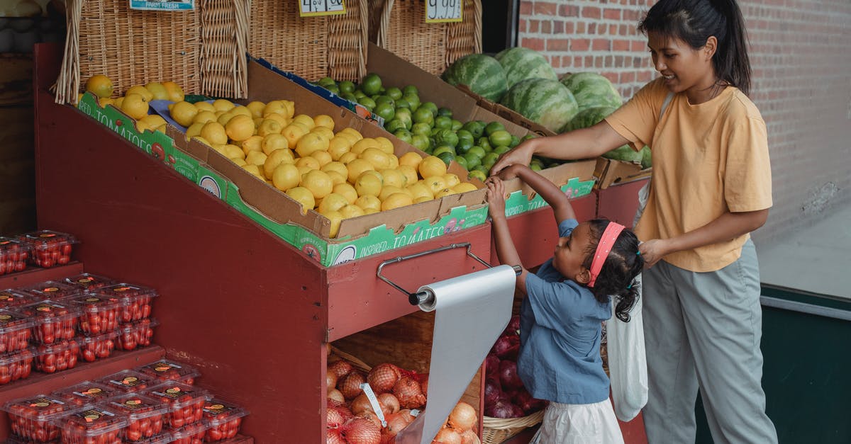 Help with friend with many allergies - Small ethnic girl taking fruits from box with mother