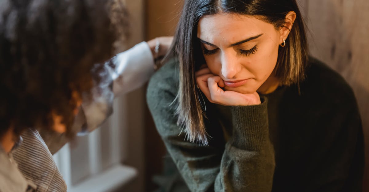 Help with friend with many allergies - Crop woman tapping shoulder and comforting upset female friend while sitting at home together