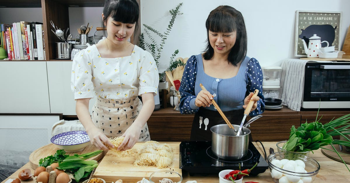 Help with thinly slicing garlic - Asian women cooking homemade egg noodles in kitchen