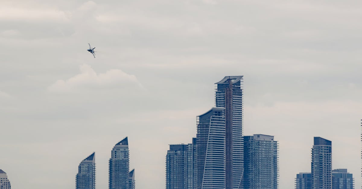 High altitude adjustment for a small rib roast needed - Military airplane flying above modern skyscrapers in city