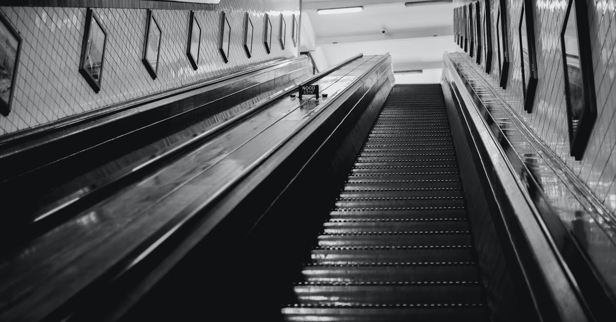 High hydration breads end up with gummy/undercooked interior - Black and white of from below of stairway with railings inside modern building with tiled walls decorated with pictures in black frames