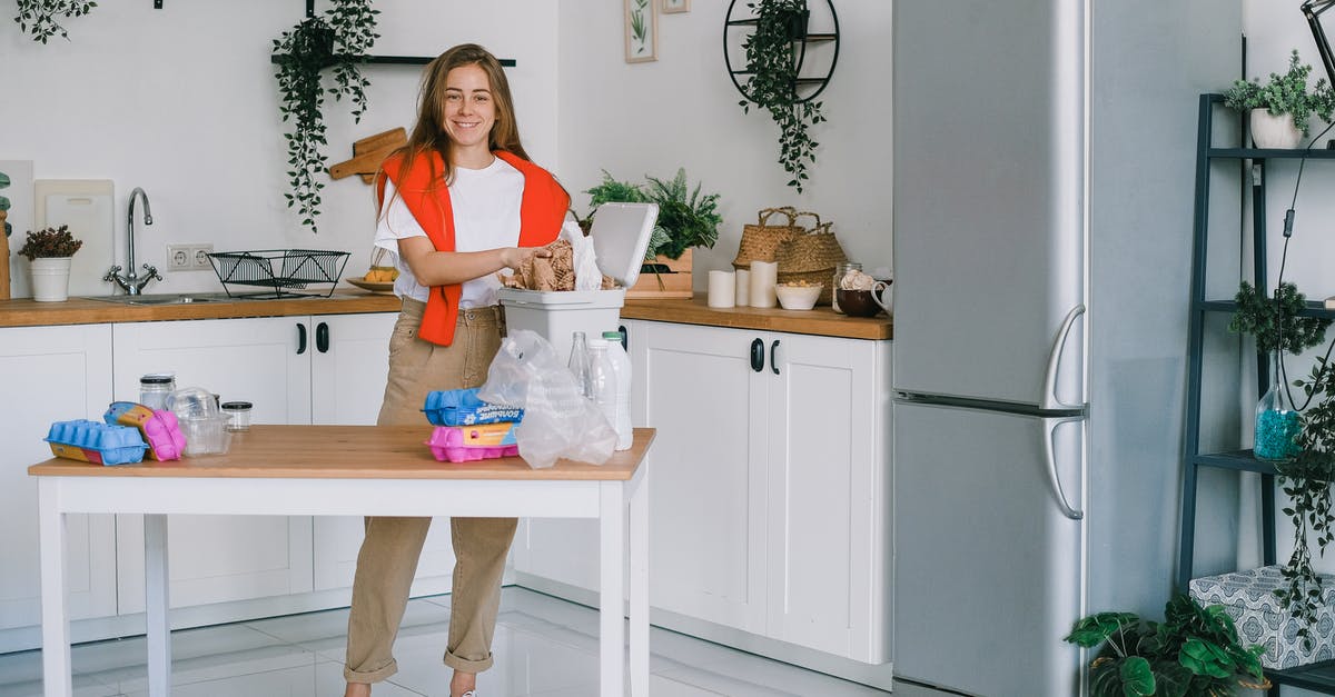 Higher or lower fridge temperature - Young woman sorting waste in kitchen