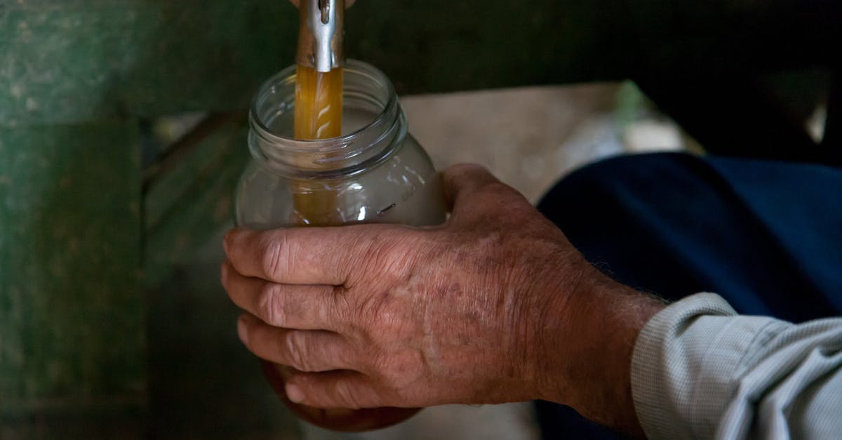 Holding sugar syrup at a consistent temperature - Person Holding Clear Glass Jar