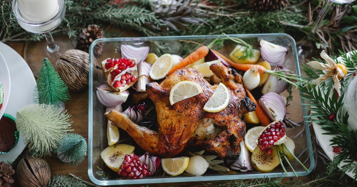 Homemade chicken nuggets: How to keep the breadcrumbs from falling off - From above of traditional Christmas roasted chicken with lemons carrots and garnet in glass plate on served table decorated with coniferous twigs