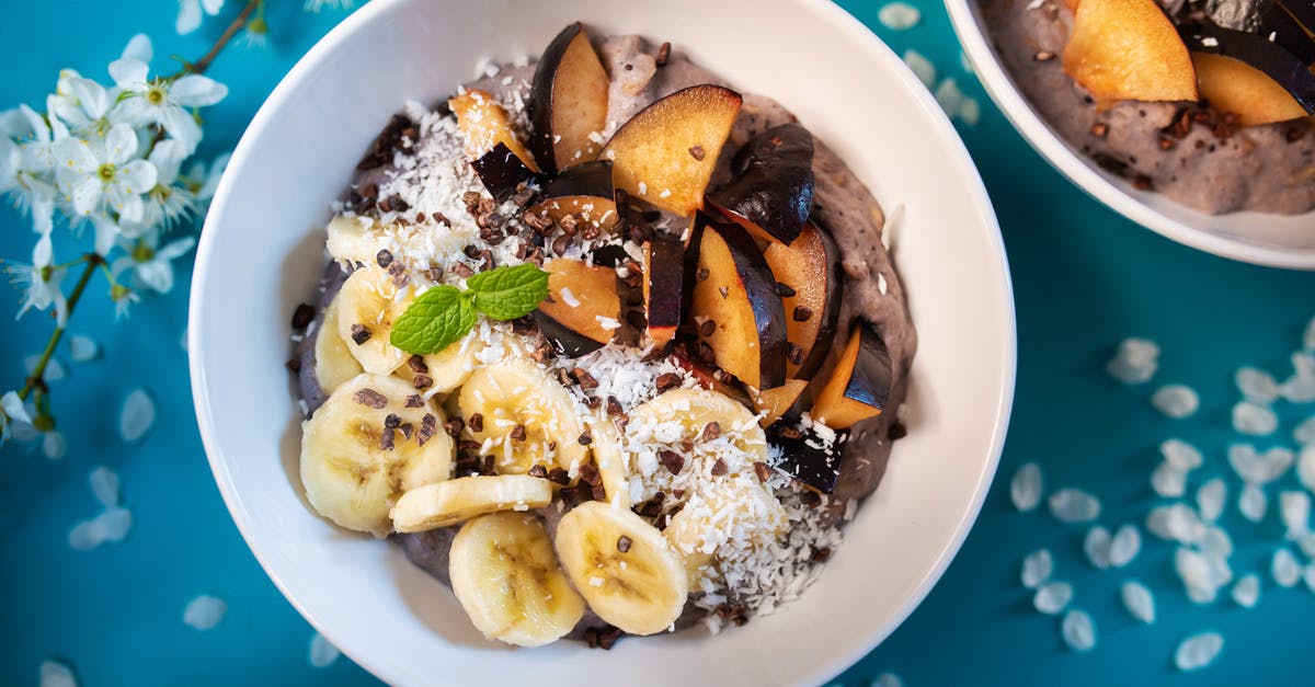 Homemade Coconut Yogurt Turned Yellow on Top Overnight - Top view of appetizing smoothie bowl topped with fresh sliced bananas and plums and decorated with coconut flakes