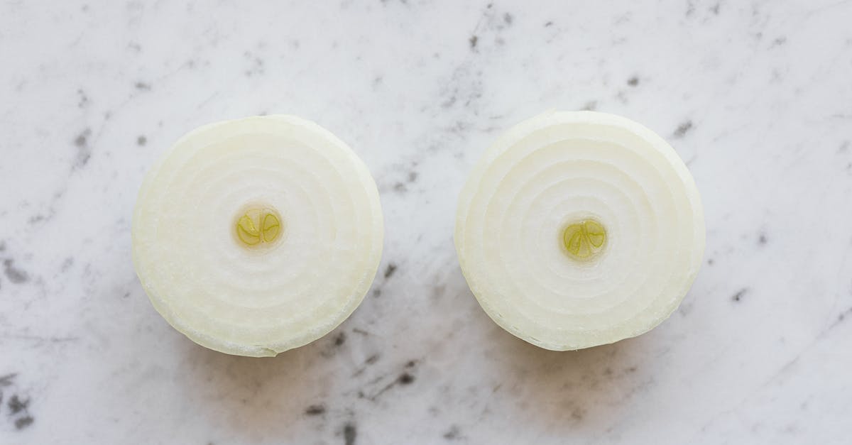 Homemade Coconut Yogurt Turned Yellow on Top Overnight - Top view of raw peeled aromatic onion cut into halves and placed on white marble tabletop