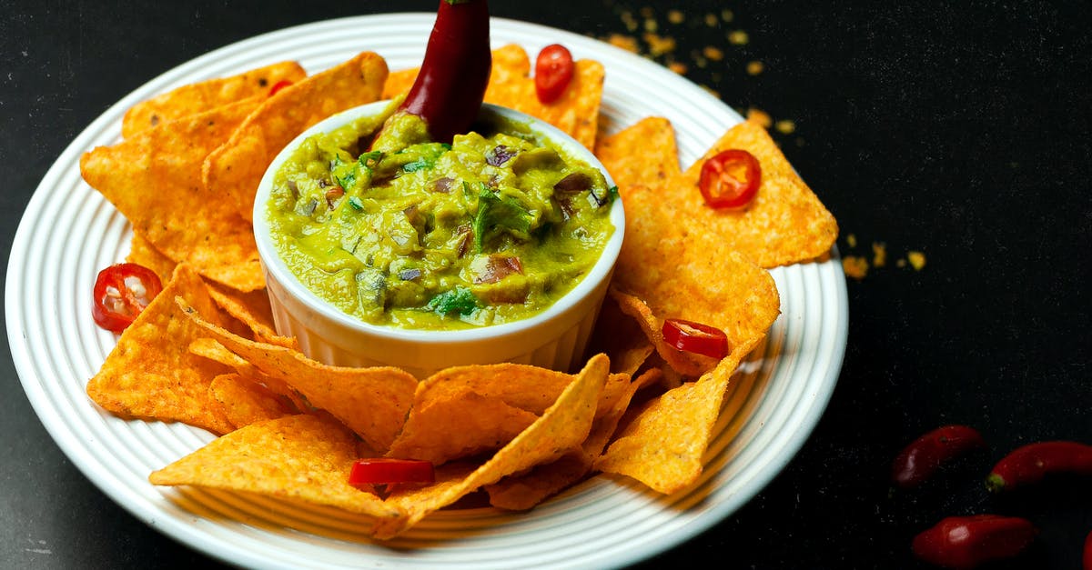 Homemade Pepper Sauce - Suggestion for a serving bottle - High angle of crispy nachos near bowl with guacamole and chili pepper on plate