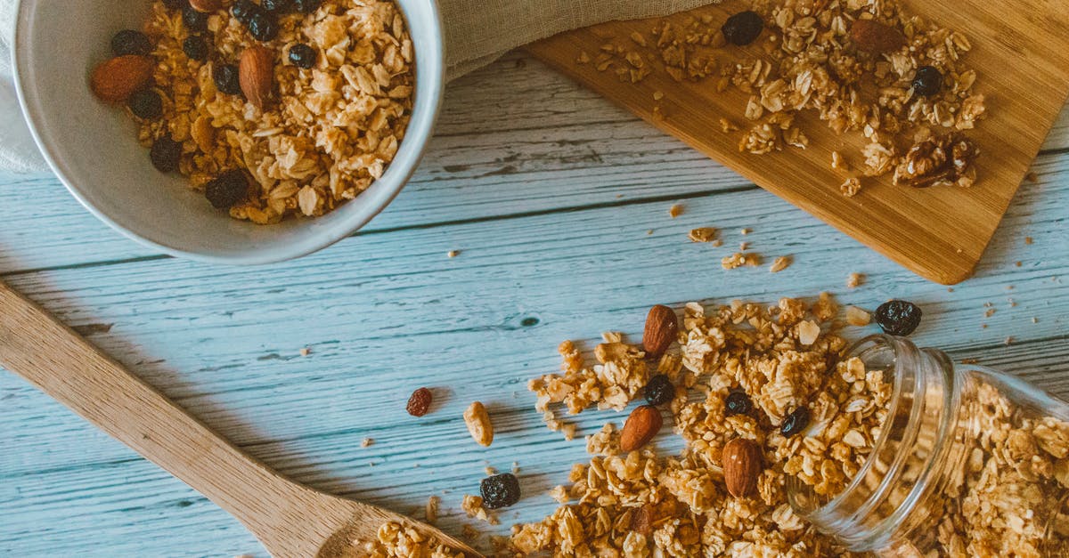 Honey in porridge - Brown and Black Nuts on White Ceramic Bowl Beside Brown Wooden Spoon