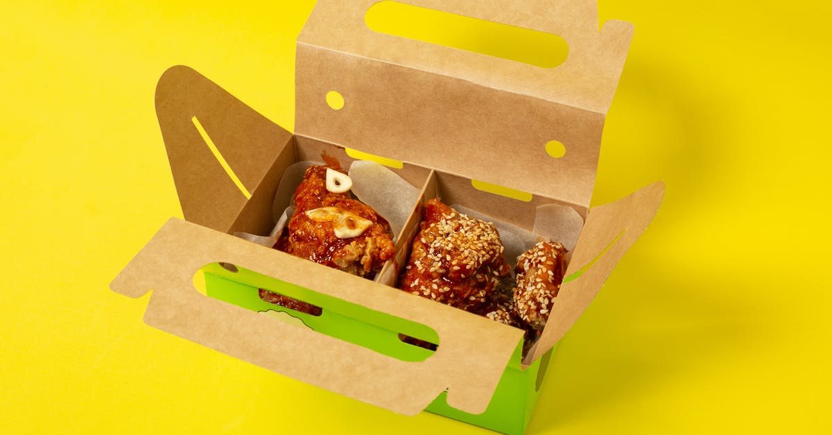 Honey-fermented garlic left open overnight - From above of appetizing chicken meat with garlic placed in cardboard box on yellow background in studio