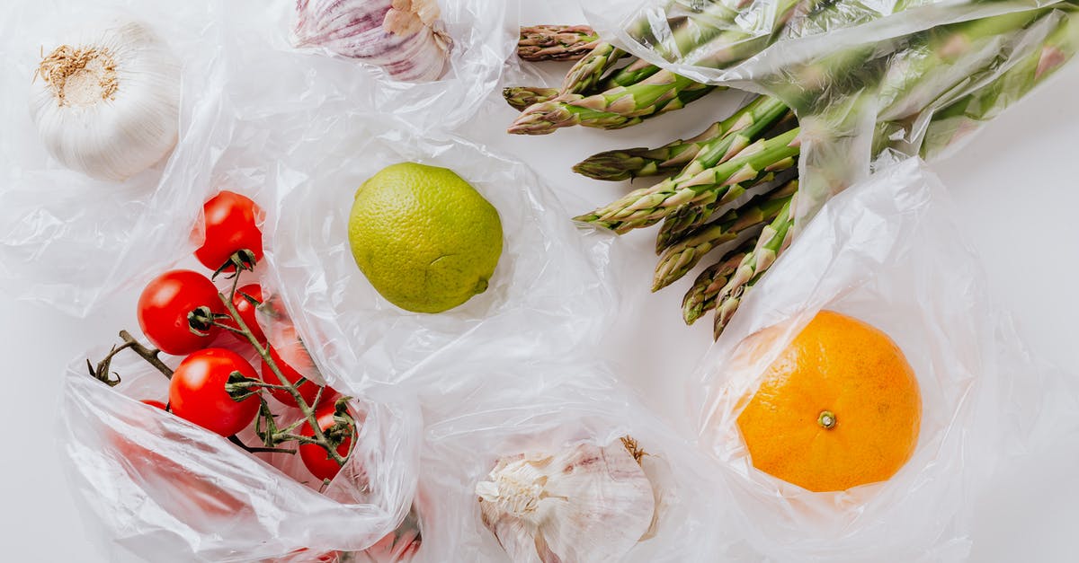How are commercial protein bars made so dense? - From above of bunch of tomatoes with raw asparagus put into transparent plastic bags on white table near citrus fruits and garlic bulbs
