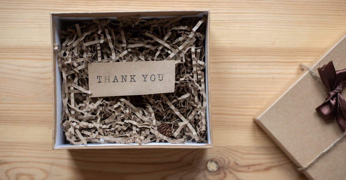 How are you supposed to eat ribbon candy? - Top view of opened carton present box with small postcard with Thank You inscription and paper stuffing on wooden table