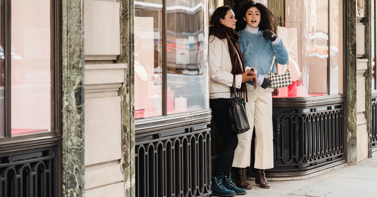 How best to store cheese long term? - Full length of young multiracial female millennials in trendy warm clothes standing on city street near aged store with glass showcases and looking away