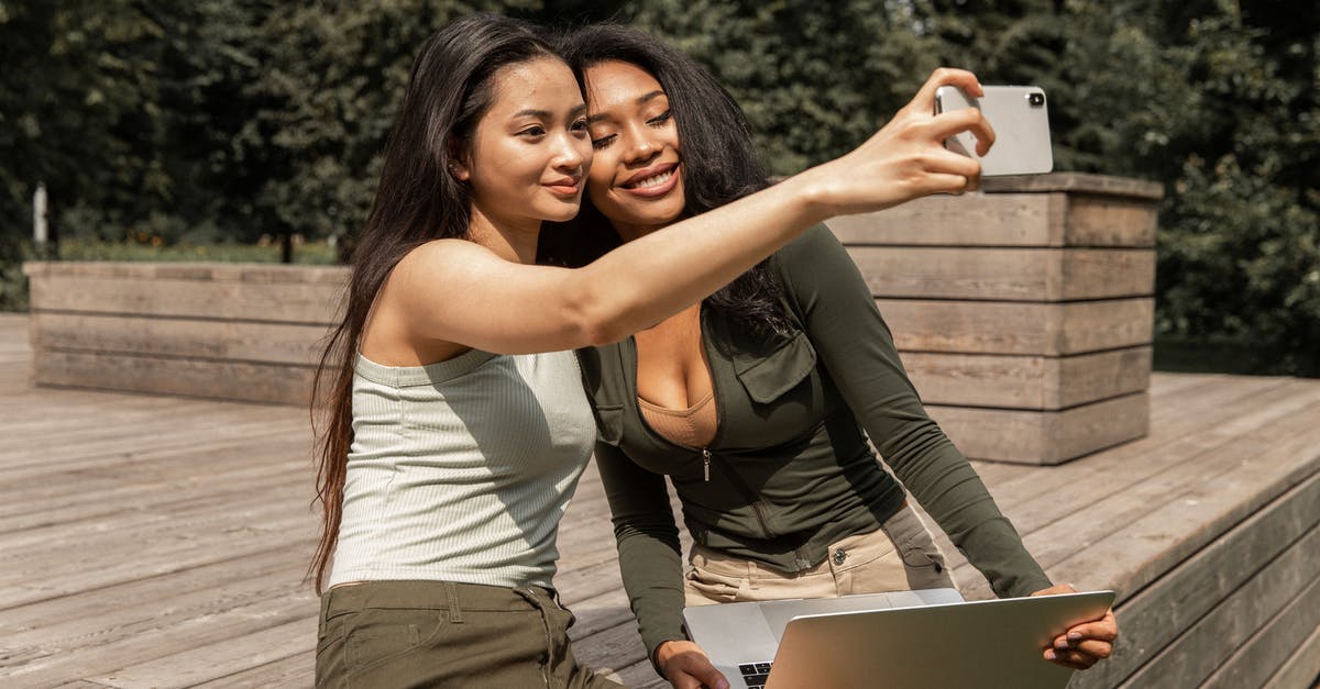 How best to use gluten free all purpose flour? - Positive young multiethnic ladies with long dark hairs in casual outfits smiling and taking selfie on mobile phone while chilling in park with laptop