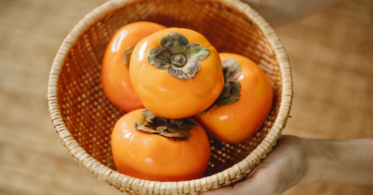 How can I add a strong orange flavor to my dishes? - From above of anonymous female with wicker bowl full of ripe orange persimmons in hands while standing on blurred background