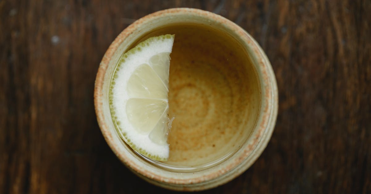 How can I add flavor to green tea at home? - Overhead view of traditional ceramic Asian cup of fresh aromatic tea with lemon slice on wooden table