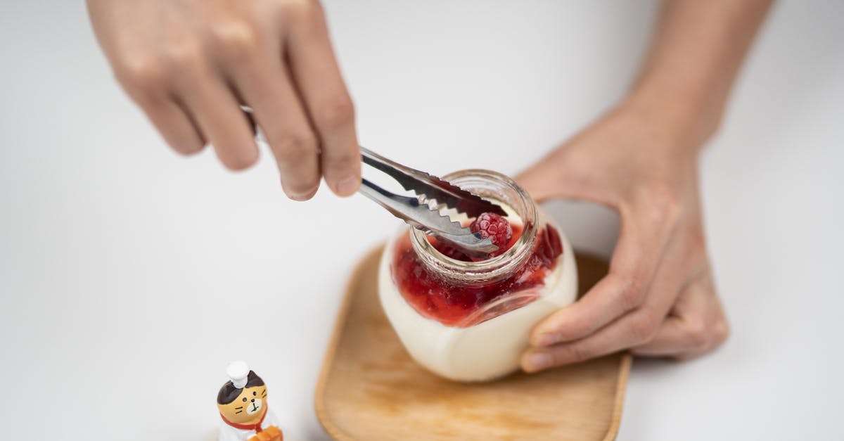 How can I add yogurt to a quickbread recipe? - From above crop anonymous person adding organic ripe raspberries into jar with homemade tasty yogurt placed on white table near funny cat statuette