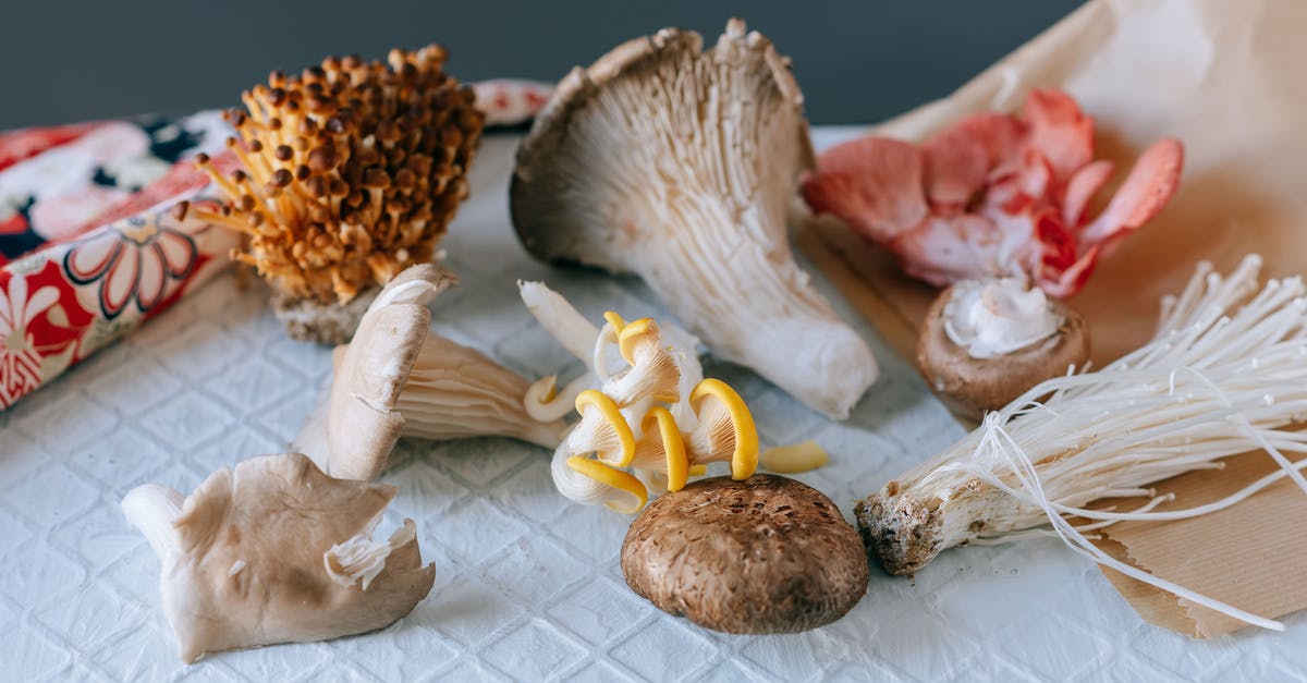 How can I avoid from turning mushrooms brown while freezing it? - From above of various exotic mushrooms placed on textured white table on green background