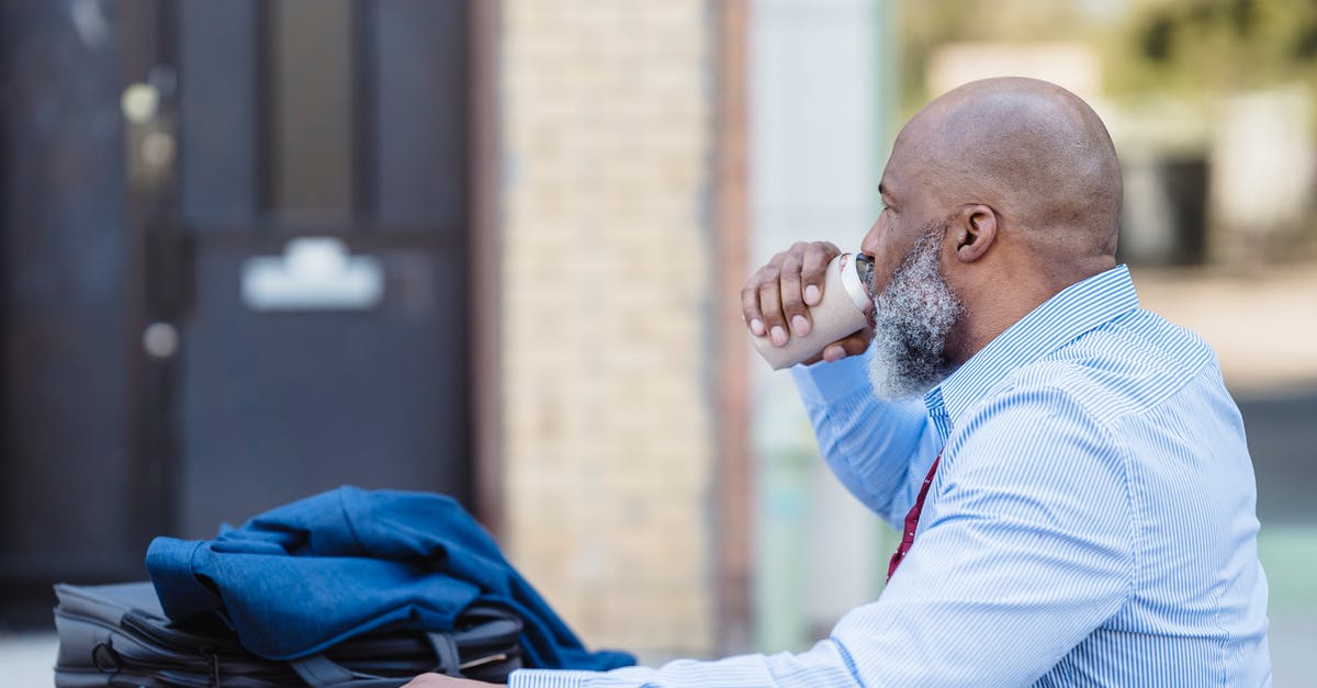 How can I break an emulsion making carotene butter? - Side view of elderly bearded African American man in trendy outfit sitting at table with jacket and handbag and drinking beverage from tin can in veranda of cafe