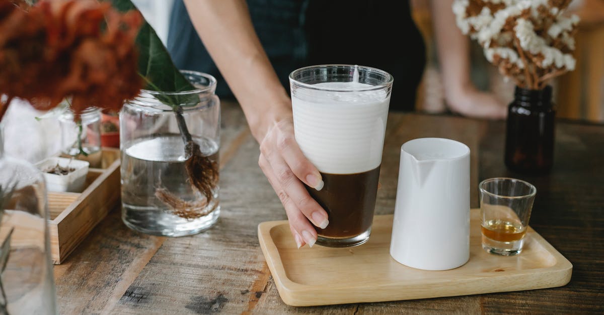 How can I brew a stronger cocoa drink? - Crop anonymous female barista serving fresh brewed iced chocolate coffee with thick layer of fluffy froth on wooden tray with shot of cognac