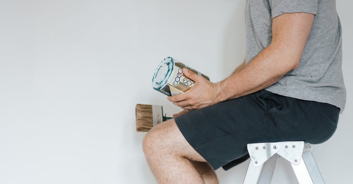 How can I clean my peeler? - Side view of crop anonymous male with professional brush and can of paint near white wall in house