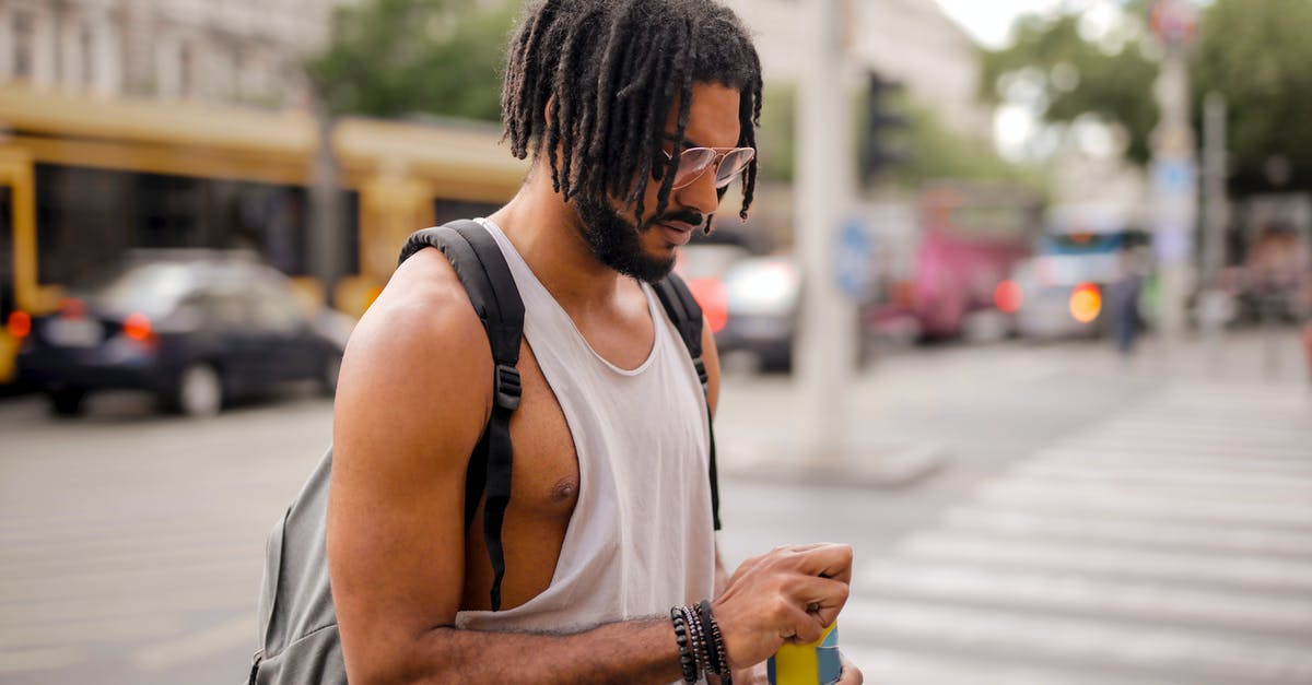 How can I cool tea quickly? - Confident adult Hispanic male traveler in sunglasses and casual clothes with backpack opening can of drink while walking along pavement against blurred cars driving along street and empty crosswalk in downtown