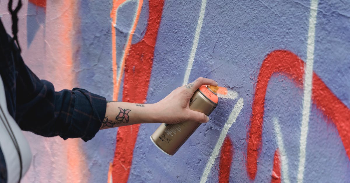 How can I create a chicken substitute? - Crop unrecognizable painter with tattoos in black wear spraying orange paint on colorful purple wall with graffiti on street of city