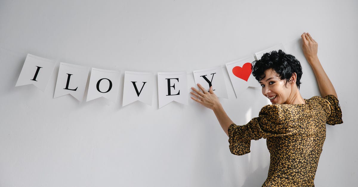 How can I decorate jelly - Cheerful female female looking at camera while hanging garland with white flags with romantic inscription on wall during Saint Valentines day