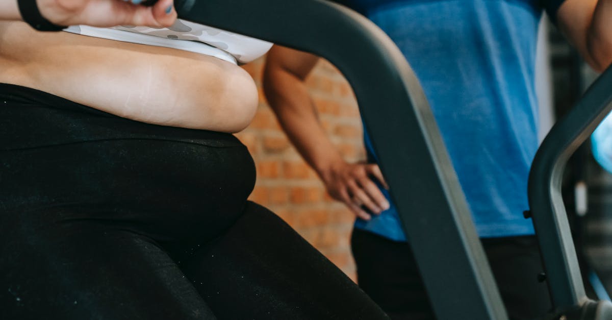 How can I determine fat content in beef? - Unrecognizable male trainer standing near plus size woman exercising on cycling machine